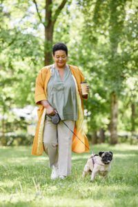 How Much Exercise Do Dogs Need? Black Woman Walking Dog in Park